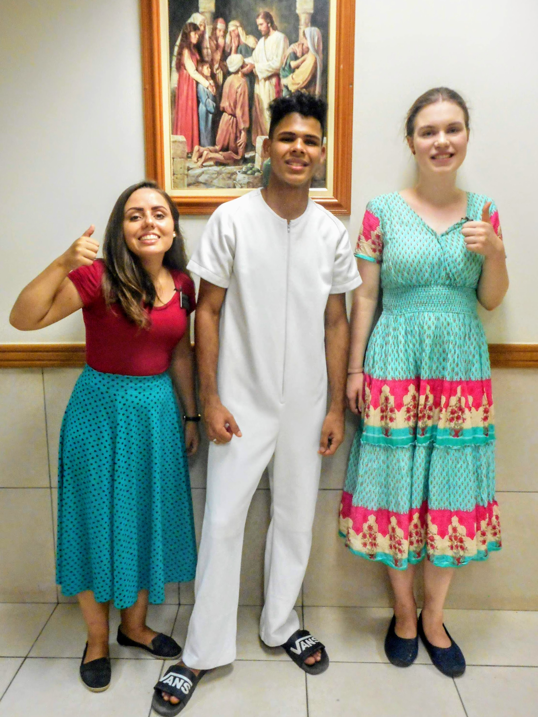 Sister Porcote, "Rafael," and sister Faulconer. The two sisters, each on one side of Rafael, are showing their thumbs up signs. Rafael is dressed in white baptismal clothing. The sisters are each wearing their church dresses.