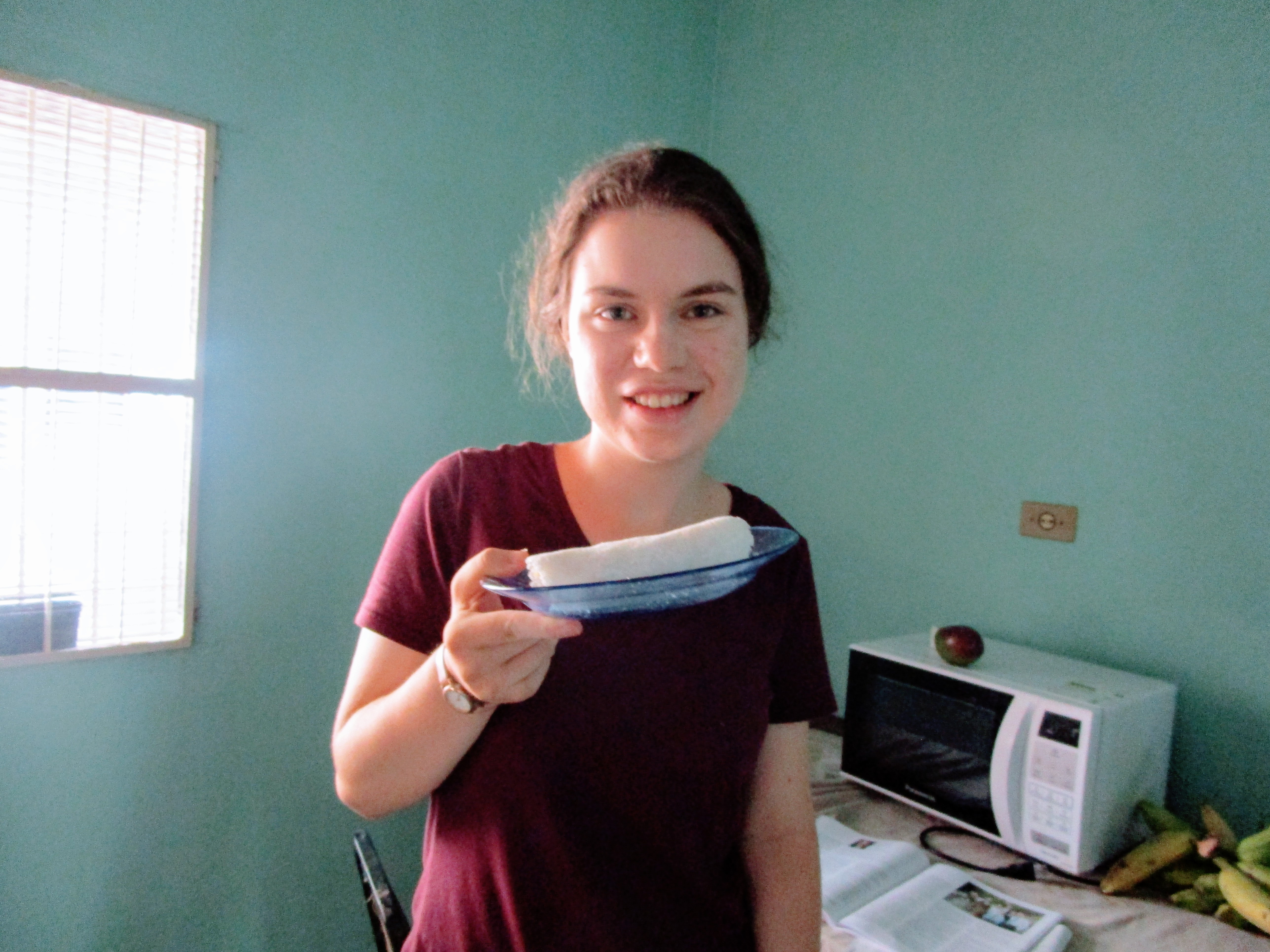 Sister Faulconer poses with a blue glass plate with a white cylinder of rolled-up tapioca on it.