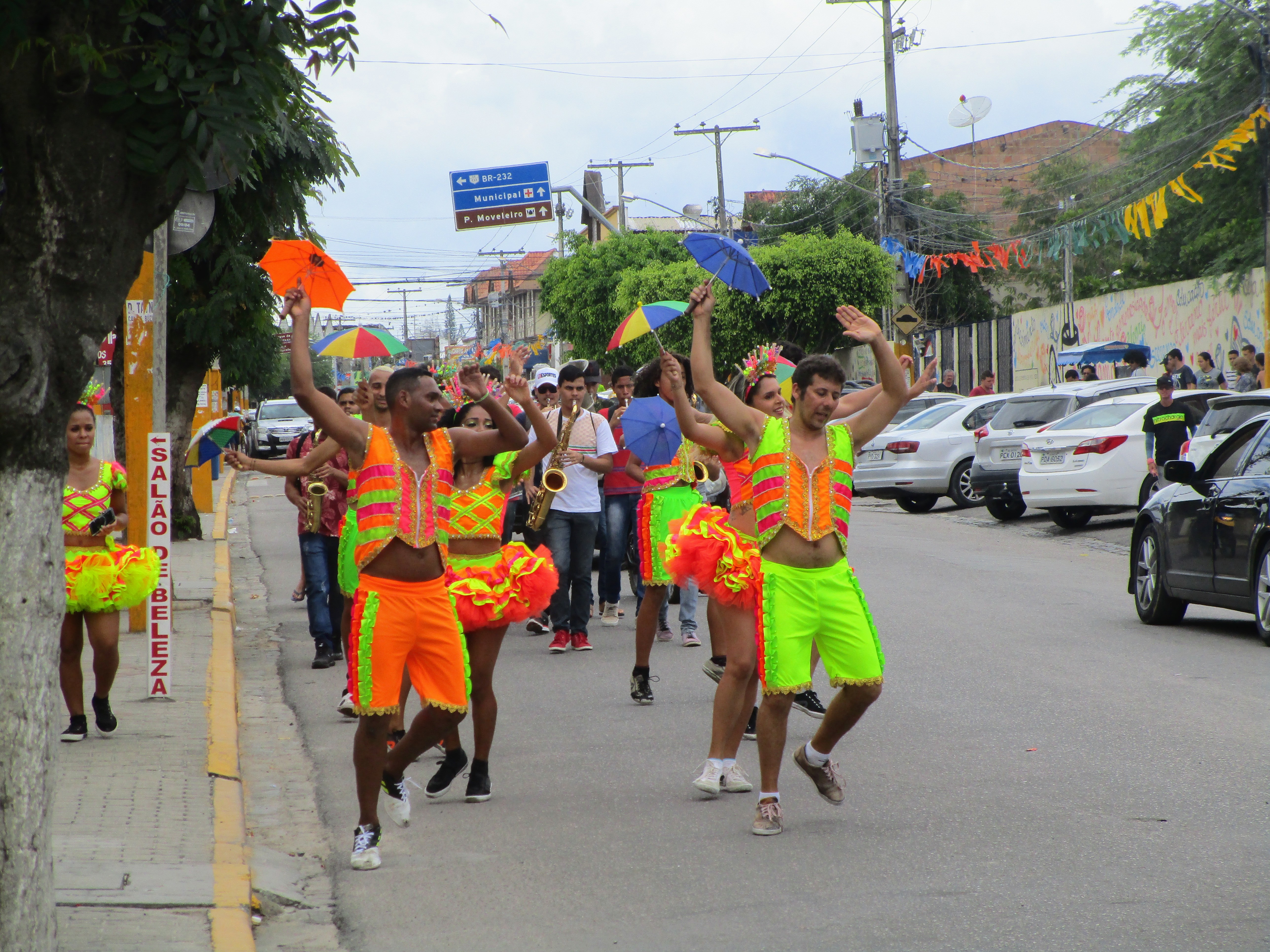 Frevo dancers holding little umbrellas and dressed in orange green and yellow neon clothing for Carnaval in Brazil